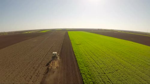 Aerial view of farmer in tractor preparing land with seedbed cultivator.