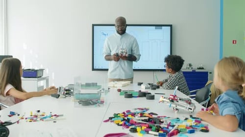 Black Male Teacher Talking to Children during Robotics Lesson