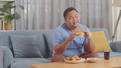 Young Adult Enjoys a Burger in Cozy Living Room