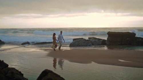 Affectionate couple enjoying a romantic moment on a cloudy beach watching the ocean