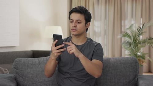 Indian man scrolling through phone