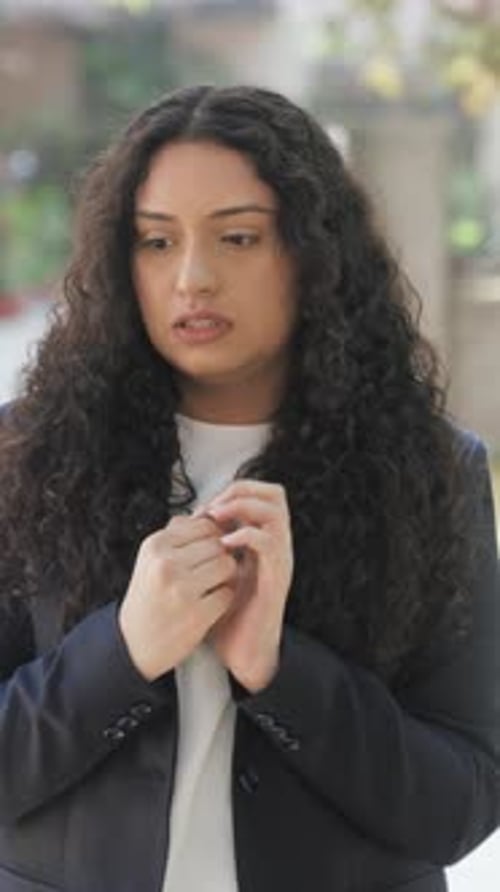 Worried Woman with Curly Hair Clenching Hands