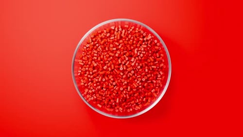 Rotating Glass Bowl with Red Plastic Polypropylene Granules Masterbatch Polymer Grain on Black