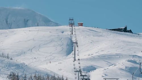Sesselliftlinie fährt den verschneiten Berghang im Skigebiet hinauf