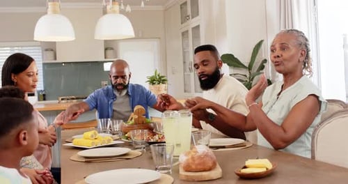 Family Holding Hands Praying Before Meal at Home
