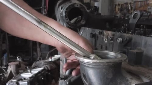 Mechanic Working on an Engine with a Tool