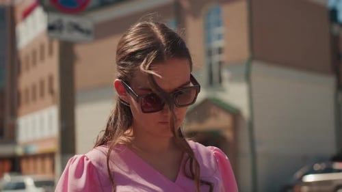 Woman in Sunglasses Standing in Urban Setting Using Phone