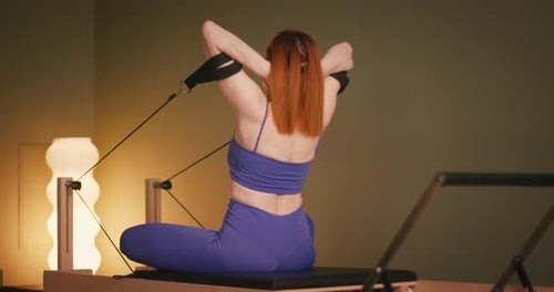 Woman Doing Pilates Exercises on Exercise Equipment