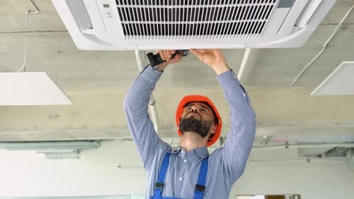 Technician Worker Installs Air Conditioning System at Office