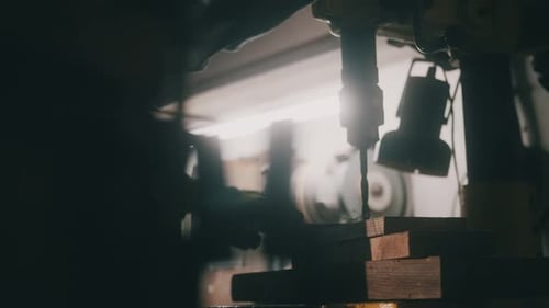 A worker works on a metal drilling machine in a workshop
