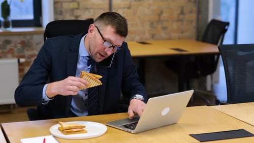 Busy Man Working at Desk on Phone Eating