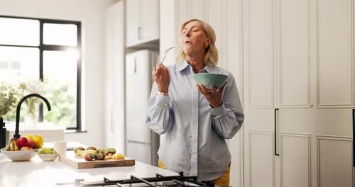 Woman Enjoys Fresh Fruit Snack in Bright Kitchen