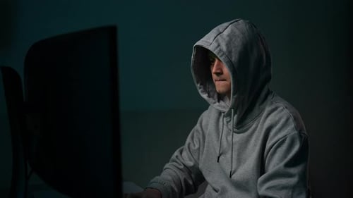 Un hacker en sweat à capuche gris tape sur le clavier et se prépare à déchiffrer son mot de passe en buvant un programmateur de café