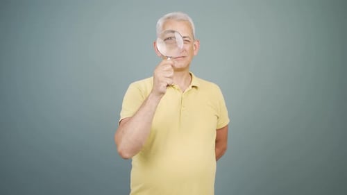 Man Looks Through Magnifying Glass and Smiles