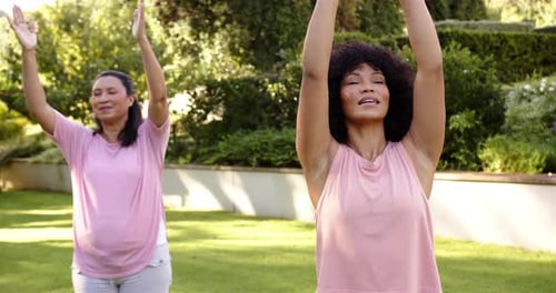 Practicing yoga outdoors, women in pink tops meditating in garden