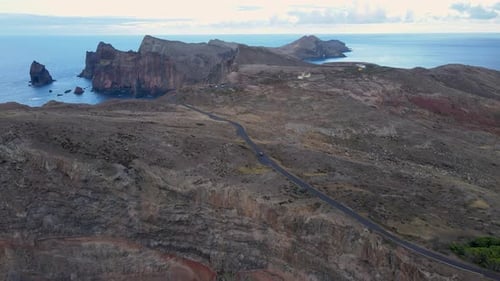 The car drives along a winding mountain road, with breathtaking views of the ocean coastline and a b