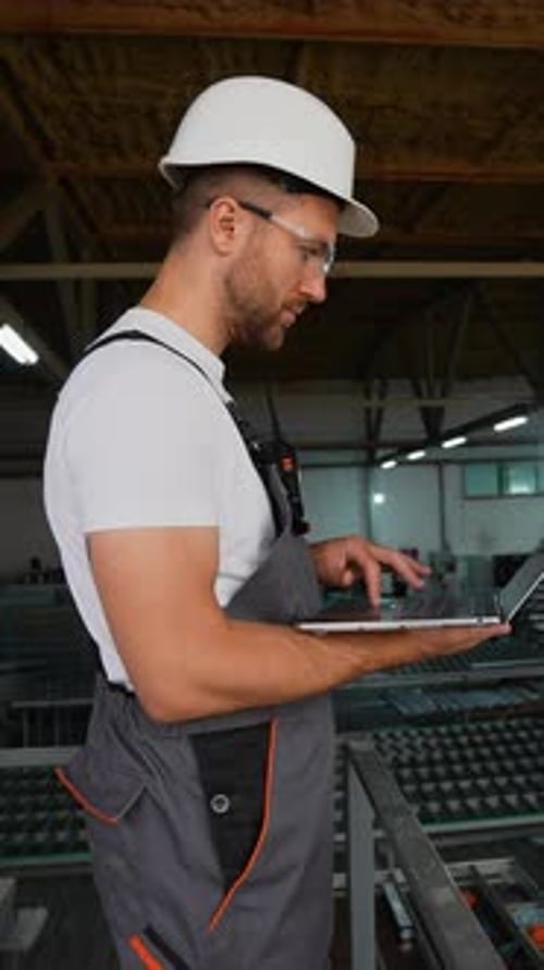 Foreman With Laptop At PVC Windows Factory Analyzes The Production Process