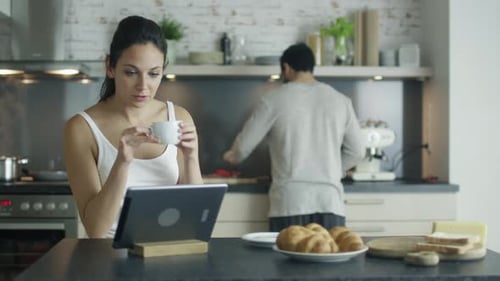 Woman Using Tablet and Having Coffee at Home