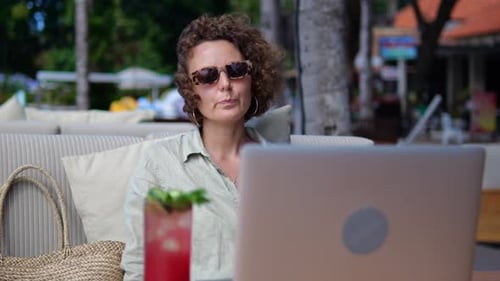 Woman Talking at Laptop in Tropical Setting