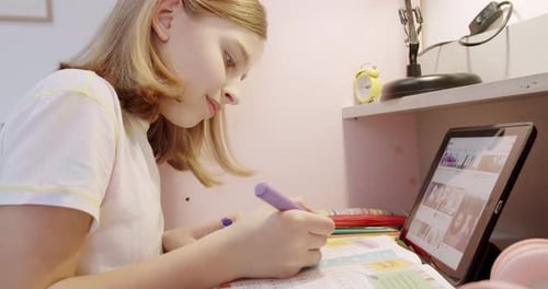 Girl Completes Homework at Desk with Tablet