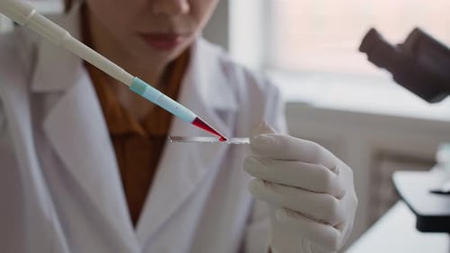 Scientist Drops Sample onto Glass Slide in Laboratory