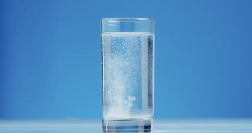 Effervescent Tablet Dissolving in Clear Glass of Water