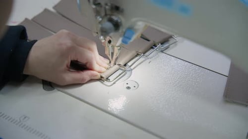Näherin händigt Stoff an einer Industriemaschine