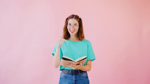 Young Woman Reading Book Smiling Giving Thumbs Up