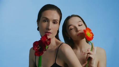 Two Women with Flowers on Blue Background