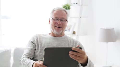 Senior Man Smiling and Using Tablet at Home