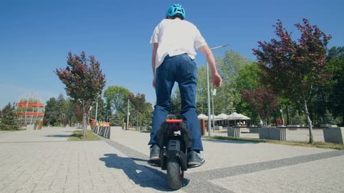Young Man Rides a Monowheel on a Sunny Day in the City Park
