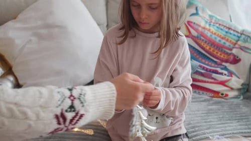 Girl and Adult Decorating Christmas Ornaments at Home