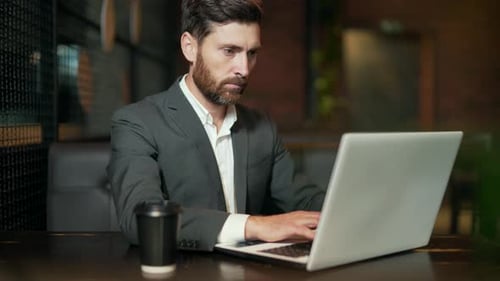 Erfolgreicher kaukasischer Geschäftsmann, der während einer Pause im Hotel, Restaurant oder Café mit Innenräumen arbeitet