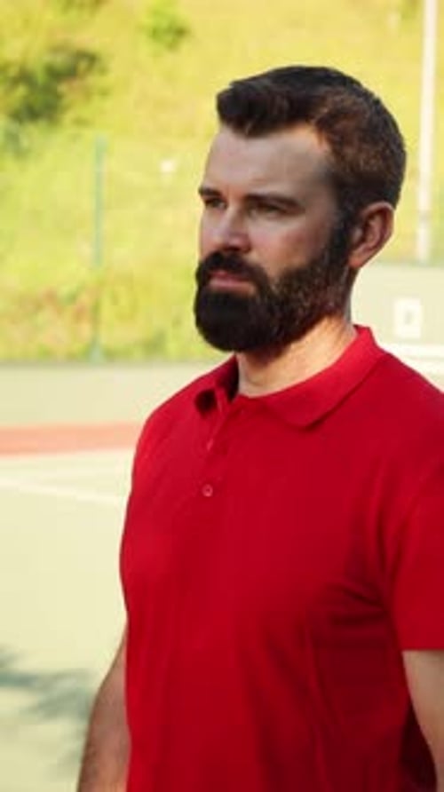 A Focused Tennis Player Wearing a Bright Red Shirt on the Court During Competition