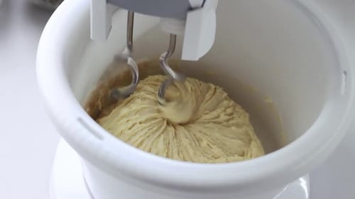 A stationary mixer with a bowl kneads the dough in slow motion.