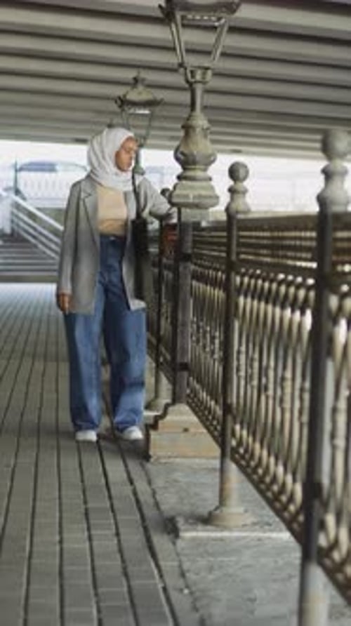 Black Muslim Woman Rests Near Handrail on City Embankment