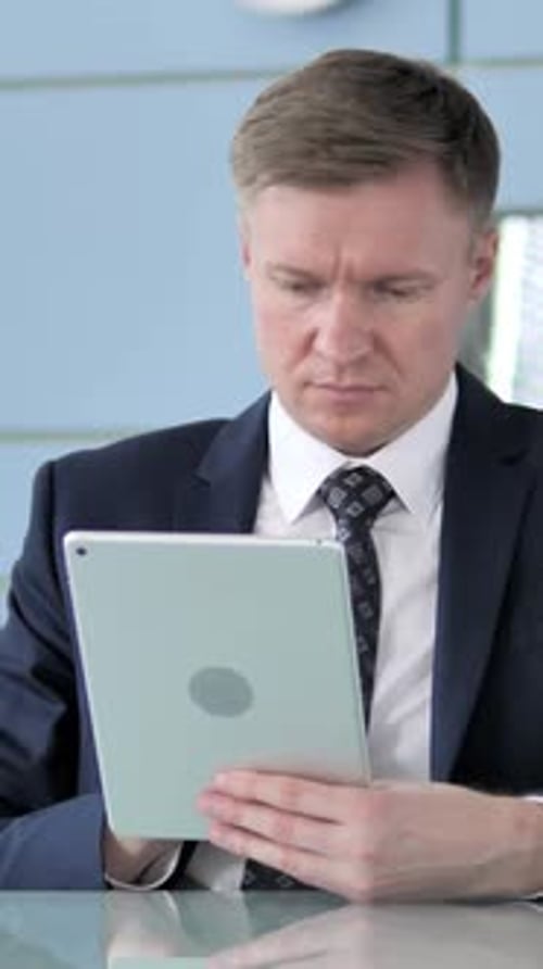 Man in Suit Uses Tablet at Desk Indoors