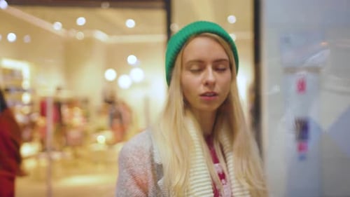 Surprised Young Woman Walking in the Hall at Big Shopping Mall and Looking on Shop Windows
