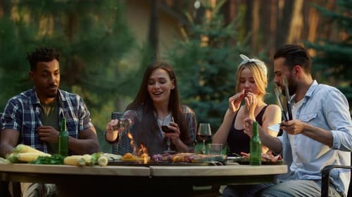 Serious chef pouring oil on bbq with friends tasting food in summer forest