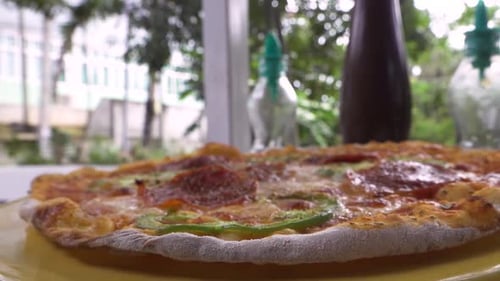 Pizza on a plate oil and pepper in the background close up moving around