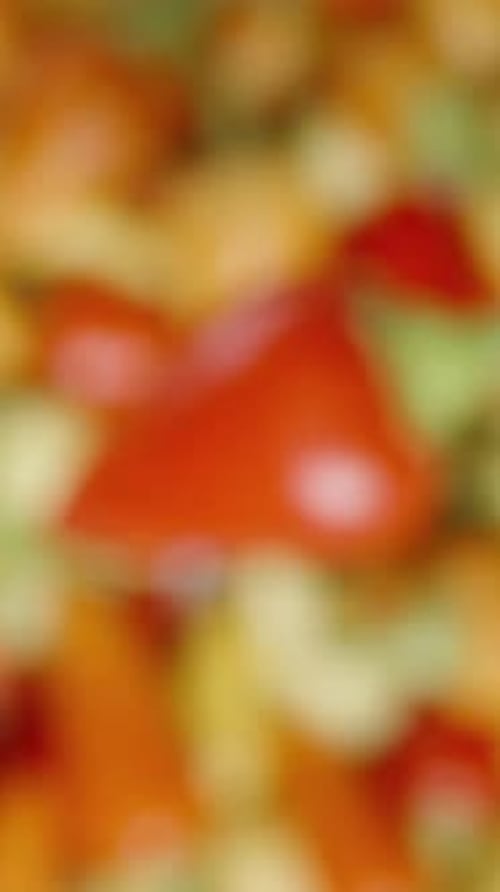 Vertical video. A red rosemary mini chili pepper rotates against the backdrop of assorted colored ch