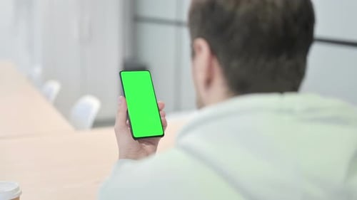 Junger Mann benutzt Smartphone mit grünem Bildschirm