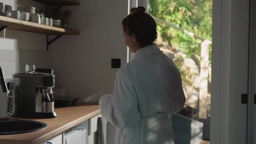 Young Woman Makes Coffee in Kitchen