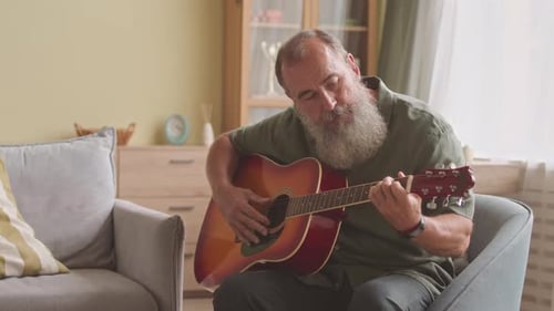 Man Plays Guitar at Home in Living Room