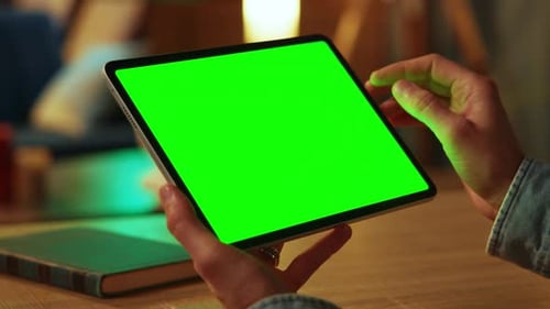 Young Man Holding Scrolling and Tapping on Tablet Computer with Horizontal Green Screen Mock Up