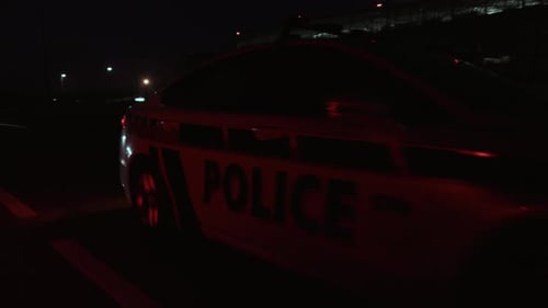 A Police Vehicle is Present at Night with Its Flashing Lights Actively Shining on the Road