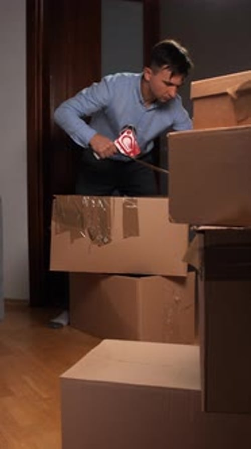 Vertical Video Man Packing Cardboard Boxes for Home Relocation