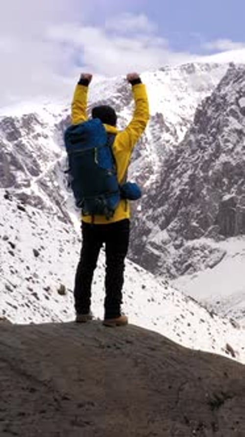 Hiker Celebrating Reaching the Summit of a Snowy Mountain