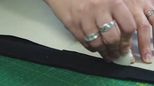 A woman marking fabric with chack next to the template. The fabric is then going to be cut to make a