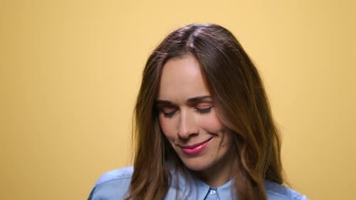 Beautiful young woman flirting with camera on yellow background in studio